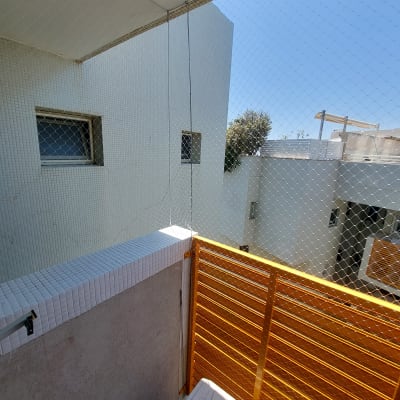 רשת הגנה נגד יונים מותקנת במרפסת עם גדר צהובה