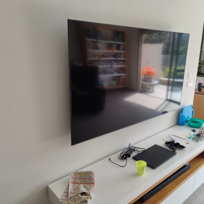 טלוויזיה תלויה על הקיר עם כבלים על השידה