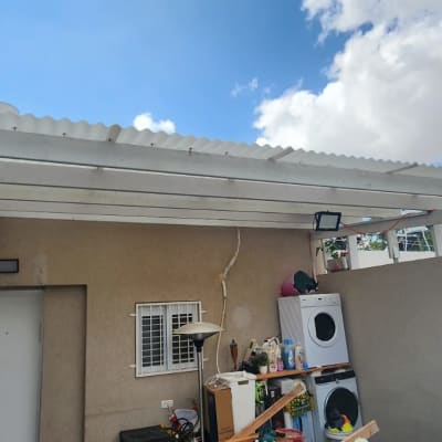 פרגולת עץ לבנה עם קירוי סנטף גלי בחצר בית