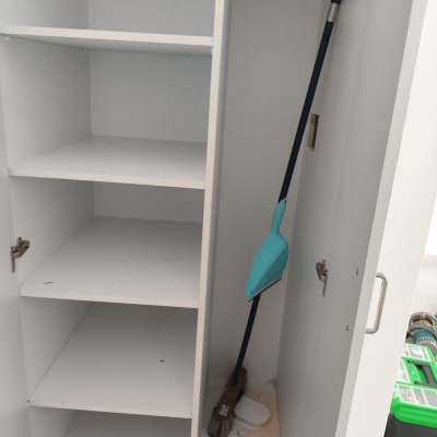 ארון פתוח עם מדפים ומטאטא בפנים