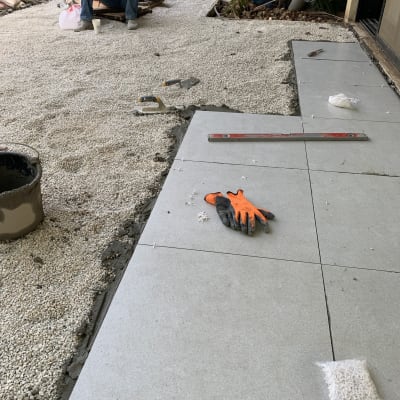 אריחים מונחים על חצץ, כפפות וכלי עבודה