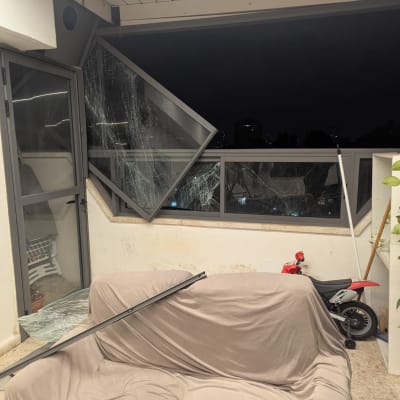 חלון שבור עם ספה מכוסה ובימבה אדומה