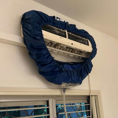 מזגן עם כיסוי כחול לתחזוקה על קיר