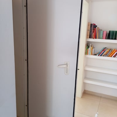 דלת לבנה פתוחה עם ידית בחדר עם מדפים