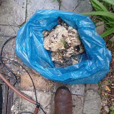 שקית כחולה עם פסולת בנייה על רצפה רטובה