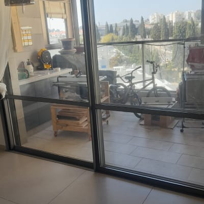 מרפסת עם תריסים פתוחים ונוף עירוני