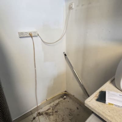 תהליך צביעת קיר פנימי בפינת חדר מרוהט בעזרת מברשת