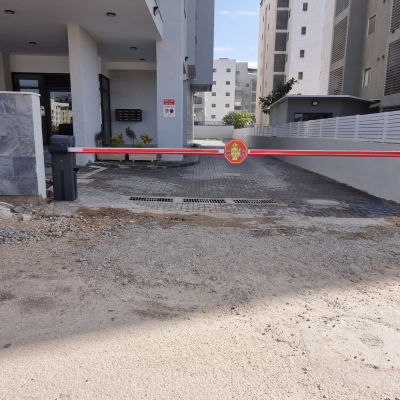 שער חשמלי עם מחסום אדום ולבן בכניסה לחניה
