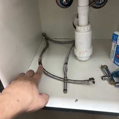 צנרת מתחת לכיור עם יד מצביעה