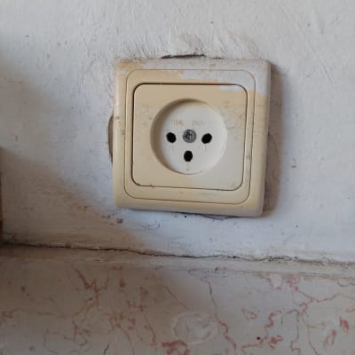 שקע חשמל ישן על קיר לבן