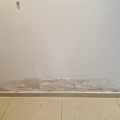 קיר עם סימני רטיבות ונזק בתחתית