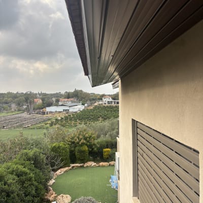 גג בית עם נוף של גינה ושדות ברקע