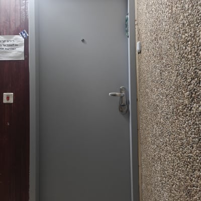 דלת אפורה עם ידית ומנעול, קיר בצד ימין