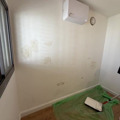 קיר עם סימני תיקון וגליל צבע על הרצפה