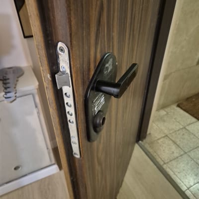 מנעול דלת עם ידית שחורה על דלת עץ