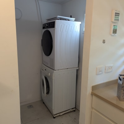 מכונת כביסה ומייבש כביסה מוערמים בחדר כביסה קטן