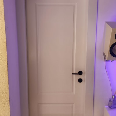 דלת לבנה עם ידית שחורה על רקע קיר סגול