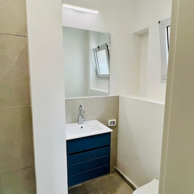 כיור עם ארון כחול ומראה בחדר אמבטיה