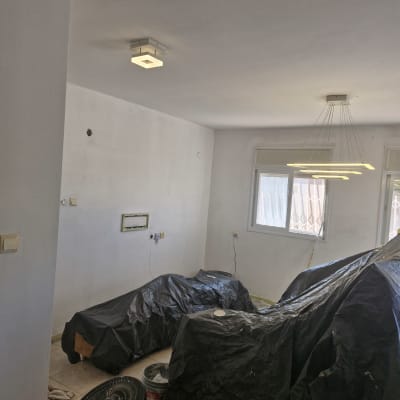 חדר עם קירות צבועים, יריעות פלסטיק ודלי צבע