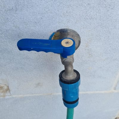 ברז מים עם ידית כחולה וצינור ירוק