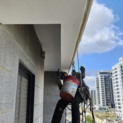 אדם תלוי על חבל מבצע עבודות גובה על בניין