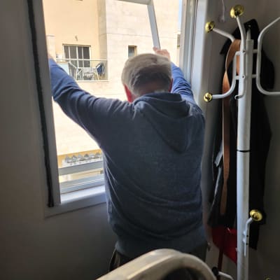 אדם מתקין מסגרת חלון חדשה לאיטום