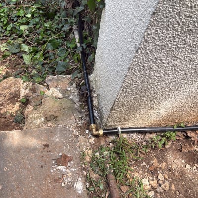 צינור מים מחובר לקיר חיצוני עם צמחייה מסביב