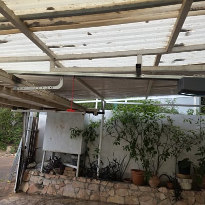 מערכת שער חשמלי מותקנת בחניה עם צמחים מסביב