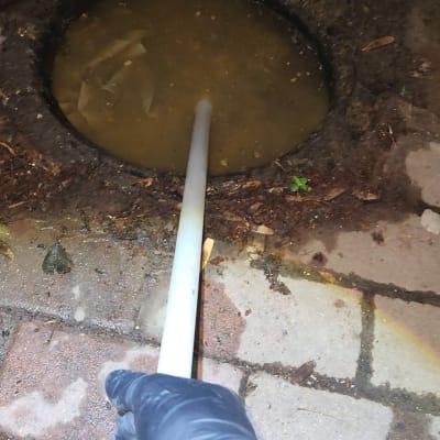 יד עם כפפה מחזיקה צינור בור ביוב