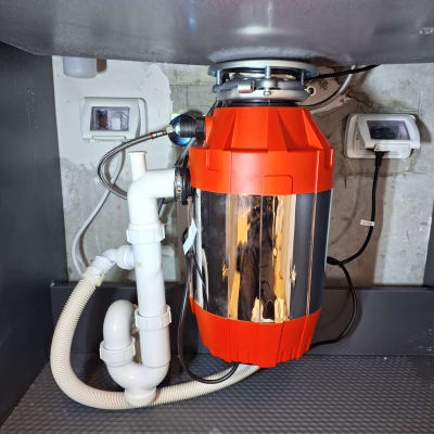 מתקן טוחן אשפה מתחת לכיור עם צינורות חיבור