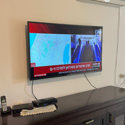 טלוויזיה על קיר עם מזגן ושלטים על שידה