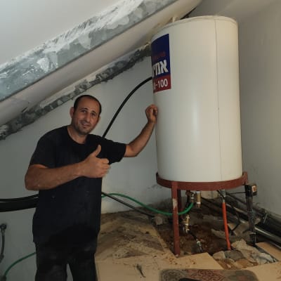 אדם ליד דוד שמש עם צינורות וחיבורים