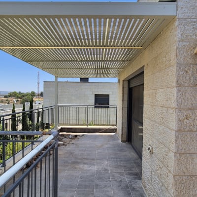 פרגולה מאלומיניום על מרפסת עם מעקה מתכת