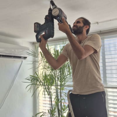 אדם משתמש במקדחה על סולם בבית