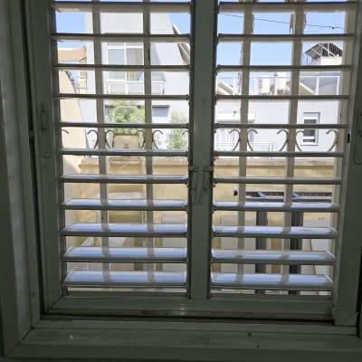 תריסים לבנים על חלון עם נוף חיצוני