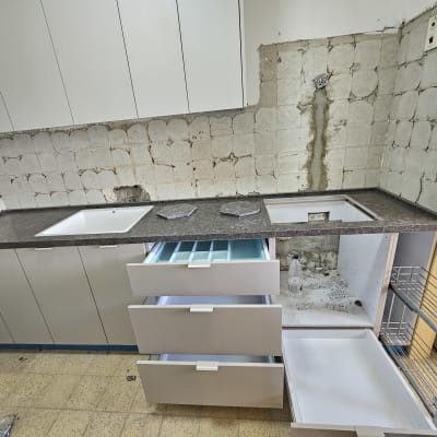 מטבח בבנייה עם ארונות פתוחים וקיר לא גמור