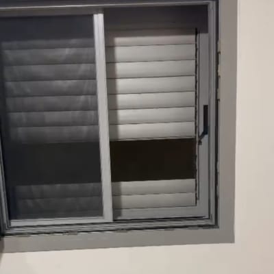 חלון עם תריסים אפורים פתוחים למחצה