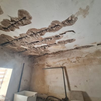 תקרת בטון מפוררת עם ברזלי זיון חשופים וחלודים במבנה קיים