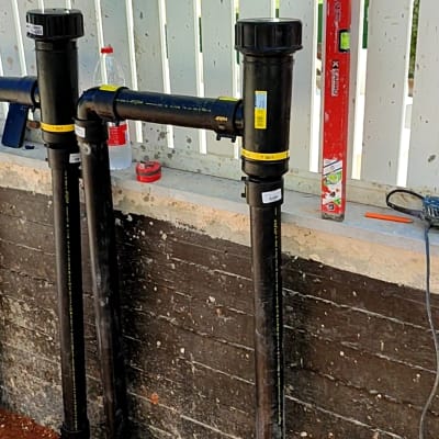 צינורות פלסטיק שחורים עם מחברים, פלס אדום על הקיר