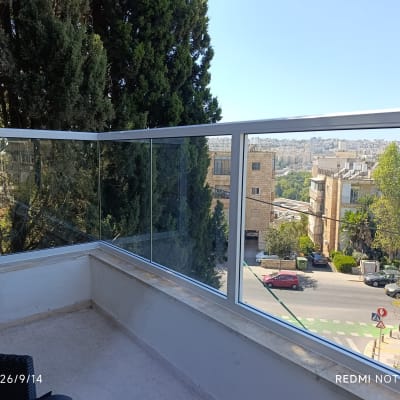 מעקה אלומיניום וזכוכית מותקן על דופן מרפסת בדירה