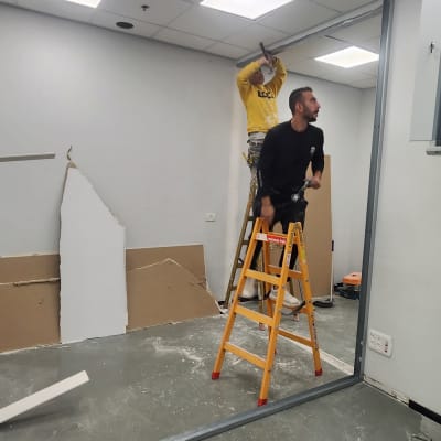 שני אנשים מתקנים קיר גבס בחדר