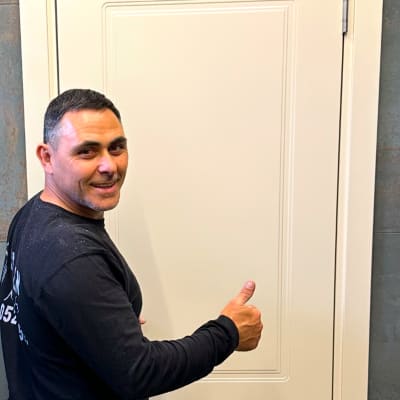 אדם עומד ליד דלת לבנה עם מסגרת פשוטה