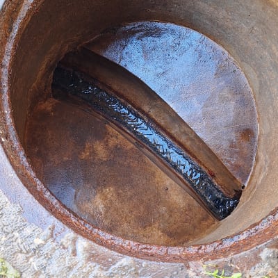 פתח ביוב עם צינור מתכת חלוד