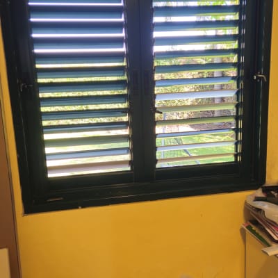 חלון עם תריסים בחדר צבוע בצהוב