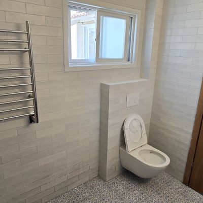 חדר אמבטיה עם שירותים וקיר אריחים