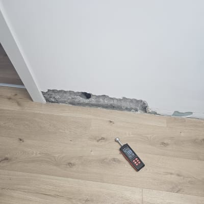מכשיר מדידה על רצפה ליד קיר עם נזק