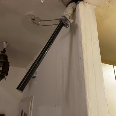 צינור מתכת עטוף בבד מחובר לתקרה פגומה