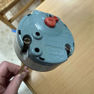 תרמוסטט כחול עם כפתור אדום על שולחן עץ