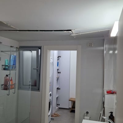 חדר אמבטיה עם תקרה פגומה, כיור ומקלחת