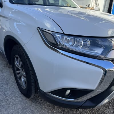 חזית של רכב לבן עם פנס קדמי מבריק ופגוש נקי לאחר טיפול פחחות